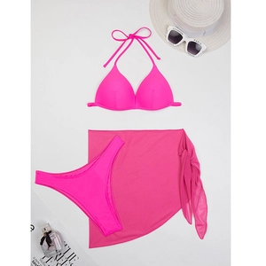 Flat lay of neon pink three-piece bikini set with sheer sarong and summer vacation props