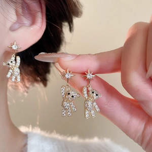 Macro shot of gold star studs and teddy bear charms with shimmering white crystals