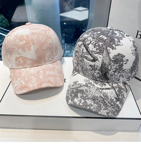 Detail view of two chic baseball caps with Toile de Jouy patterns on a display stand
