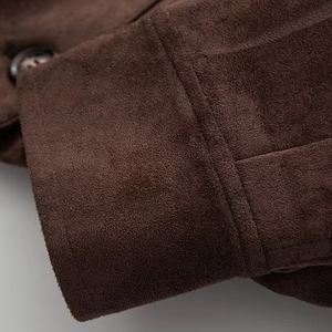 Detail of dark brown faux suede jacket sleeve with precise stitching and button cuff