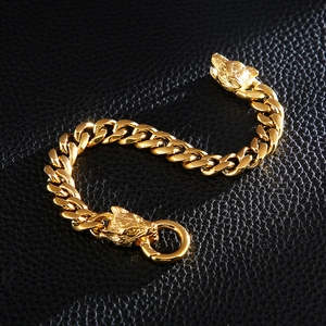 Detailed close-up of golden Cuban link bracelet with engraved wolf heads on black leather