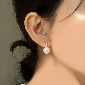 Close-up of minimalist pearl drop earrings with zircon detail on female model