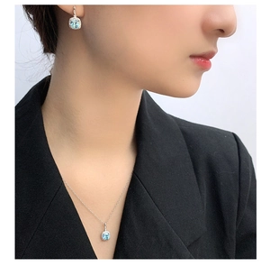 Detail view of light blue square cut gemstone necklace and earring set on a model