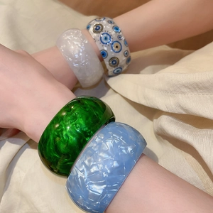 Detail of colorful wide acrylic resin bangles with marble textures and evil eye patterns