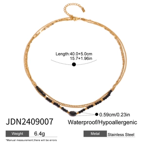 Detail of layered gold stainless steel necklace with black beads and crystal pendant