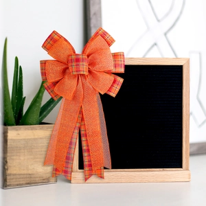 Thanksgiving pumpkin bow decoration in orange burlap and striped plaid for fall harvest