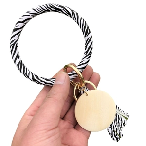 Zebra print leather wristlet keychain with wood tag and tassel held in hand