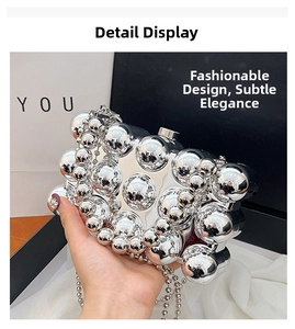 Close-up of silver acrylic clutch bag featuring polished chrome spheres and bead chain strap