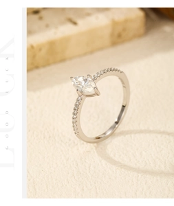 Macro detail of marquise cut moissanite ring with pavé set diamond band on stone background