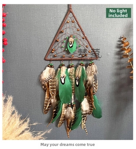 Detail of triangular dreamcatcher with brown webbing, green feathers, and wooden beads