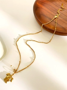 Detailed close-up of golden sea turtle pendant with pearl on a fine bead chain