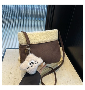 Détail du sac bandoulière en daim marron et peau de mouton avec charm petit chiot blanc