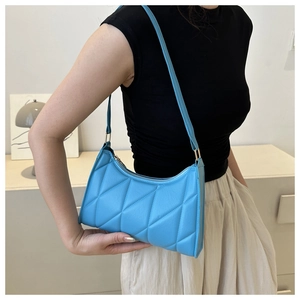 Detail of bright blue quilted baguette bag with diamond pattern and gold buckle detail