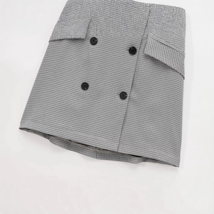 Flat lay of a grey plaid mini skirt with double-breasted buttons and wrap design