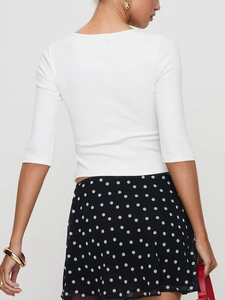 Rear view of light blue slim fit knit top with polka dot skirt on a model in studio