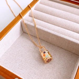 Vue détaillée du collier doré avec motifs floraux en émail coloré et petits strass brillants
