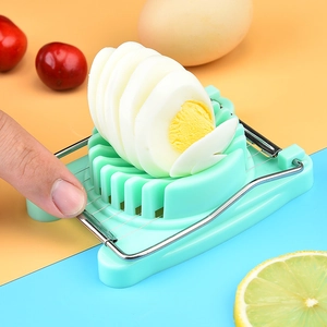 Manual plastic egg slicer with metal wires showing slicing action on a boiled egg