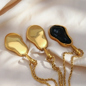 Three organic droplet pendants in gold and black finish on textured beige silk