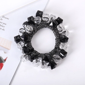 Detail of hand-woven hair tie with multifaceted black and clear beads on white background