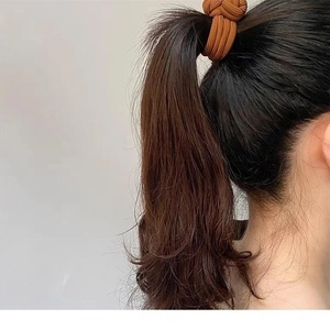 Close-up of a brown knotted elastic hair tie worn on a ponytail for hair styling