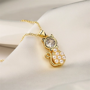 Detailed macro view of a gold cat pendant featuring a zircon head and white pearl body