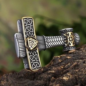 Macro shot of silver and gold Viking Mjölnir pendant with Valknut symbols on bark