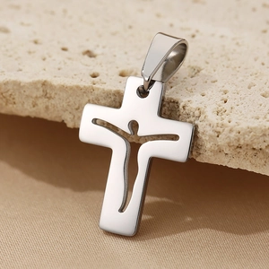 Detailed macro view of a silver cutout cross pendant resting on a textured beige stone