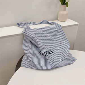 Detail of blue and white striped canvas tote bag with SUNDAY lettering on white desk