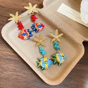 Detailed shot of starfish and tropical fish drop earrings in a simple eco-friendly box