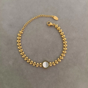 Detailed view of 18K gold titanium heart-link bracelet with round white mother of pearl