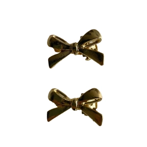 Pair of elegant gold metallic bow hair clips on white background for women styling