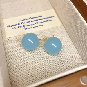 Vue macro de boucles d'oreilles sphériques bleu clair avec tiges dorées en écrin