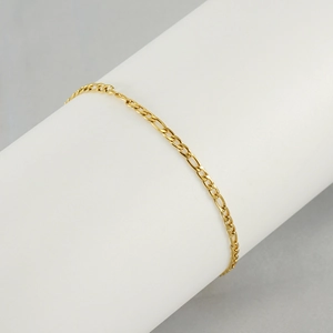 Detail view of a gold Figaro link chain anklet wrapped on a white cylinder stand