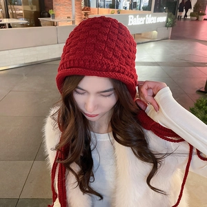 Detail of red handmade crochet knit hat with ear flaps and long braided tassels