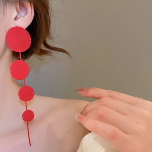 Detail of red tiered circular earrings showing delicate spiral texture and geometric style