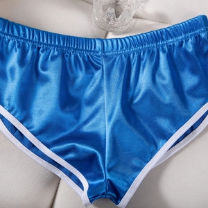 Dettaglio macro di pantaloncini sportivi in raso blu lucido con finiture bianche a contrasto