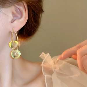 Close-up of elegant gold cherry earrings with translucent yellow-green resin beads