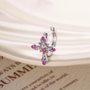 Bohemian silver cross hoop earrings with pink and purple crystals on book background