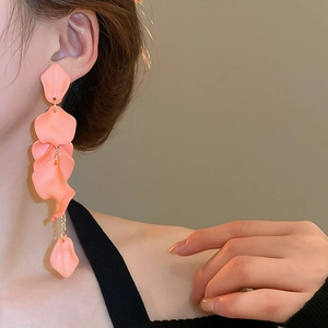 Macro detail of long tassel earrings with layered pink rose petals on gold chains