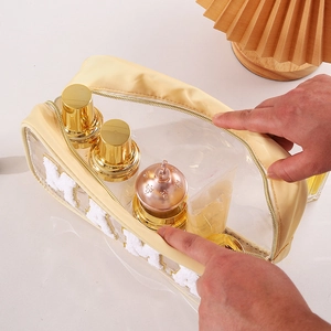 Macro shot of a beige transparent PVC makeup bag with a plush letter M and gold zipper
