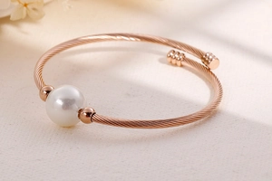 Vue détaillée du bracelet torsadé en or rose orné d'une perle blanche élégante