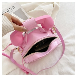 Pink retro telephone shaped crossbody bag showing interior storage for makeup items