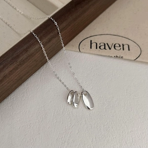 Minimalist 925 sterling silver necklace featuring three irregular oval pendants on a wood tray