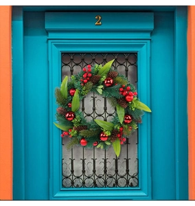 Detail of Christmas wreath with red berries, pine cones and balls on a blue wooden door