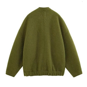 Detail view of the grass green textured fabric and ribbed hem on a loose bomber jacket