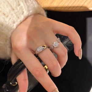 Close-up of polished silver rings with zircon floral patterns worn on a hand