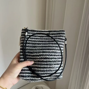 Detail of black and white striped knit bag with leather strap and simple logo label