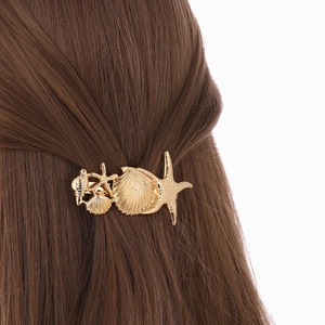 Golden alloy hair clip featuring sea stars and shells on long brown hair back view