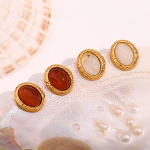 Close-up of vintage 18K gold-plated oval stud earrings with natural stone on shell