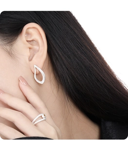 Detail of S925 silver hollow drop earrings with brushed texture and a double-layer ring